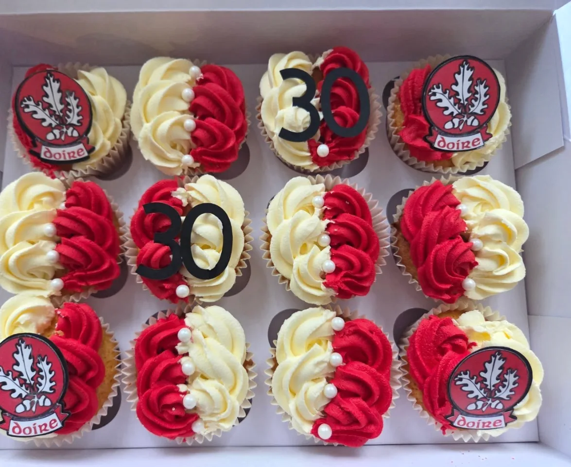 Twelve cupcakes in red and cream swirls, with Derry GAA crests and black 30 toppers